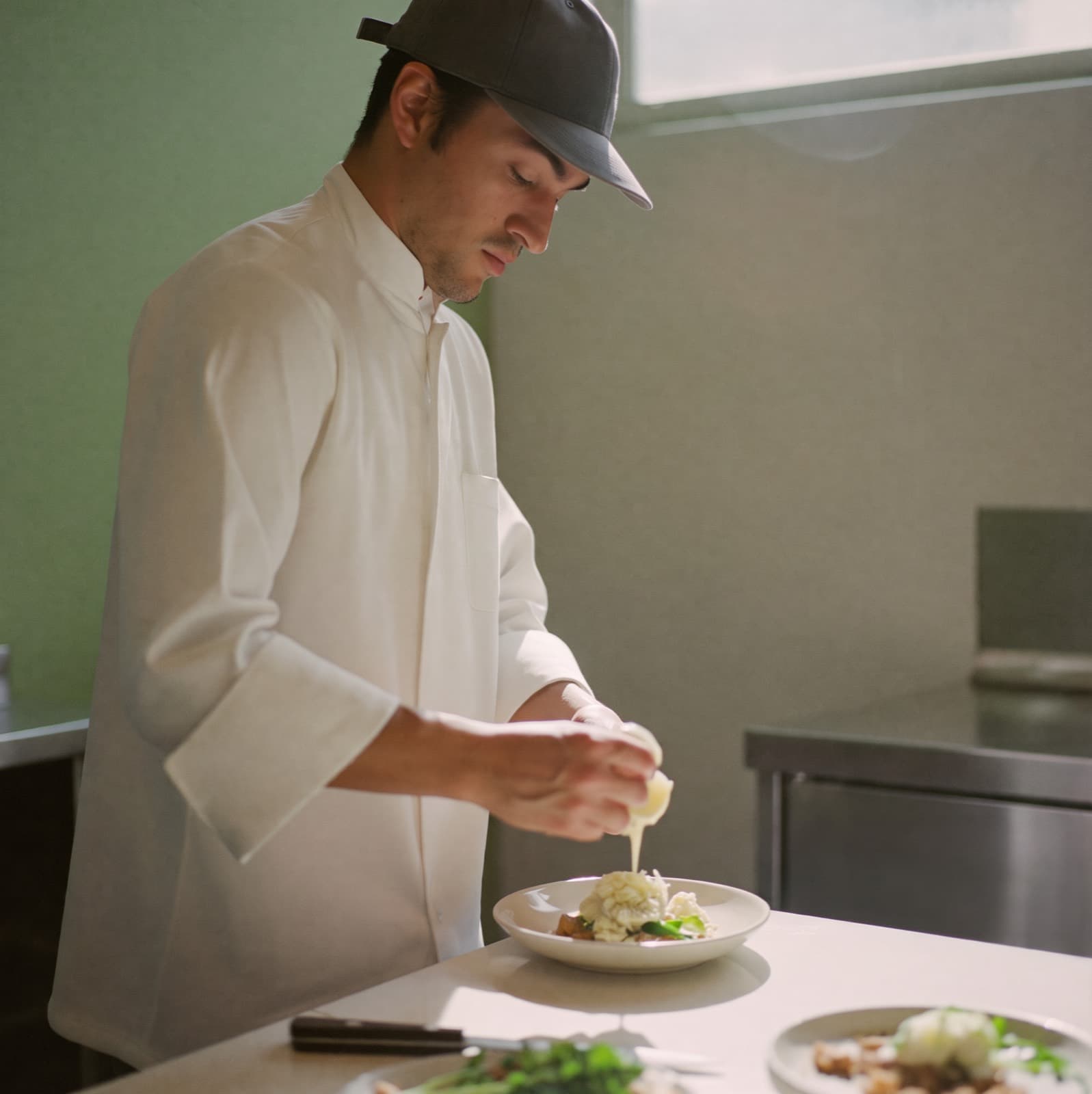 Un cocinero termina un platillo en una cocina limpia y moderna.